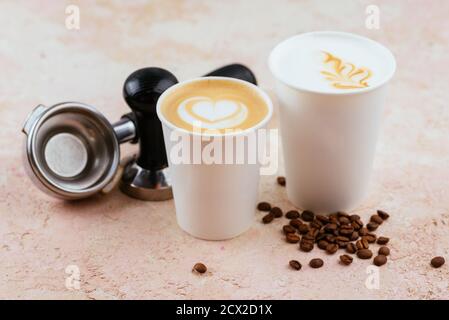 Cappuccino und Latte in Einweg-Pappbecher auf einem Licht Hintergrund mit Kaffeebohnen Stockfoto
