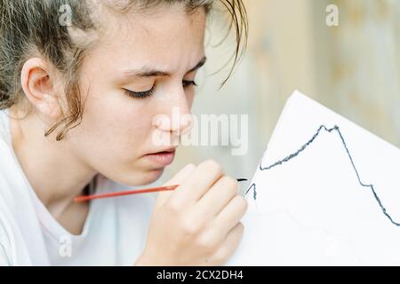 Weißes Mädchen Malerei mit einem Pinsel ihr Bild beginnend mit schwarzen Pinsel stoke. Horizontales Foto Stockfoto