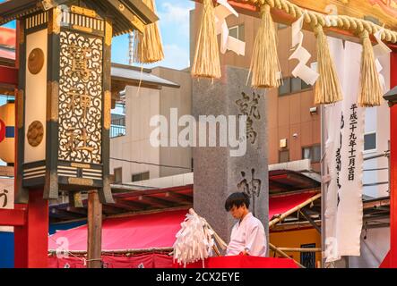 asakusa, japan - november 08 2019: Junger japanischer Negi-Junge in traditionellem jōe Kimono, der die Gläubigen mit einem Ōnusa im Shinto Ootori segnet Stockfoto