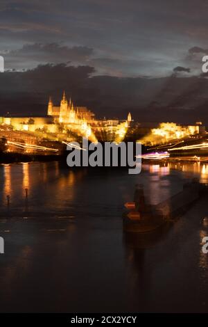 Psychedelische, verschwommene Stadtansicht von Prag bei Nacht beleuchtet mit der Moldau und St. Veits Kathedrale Stockfoto
