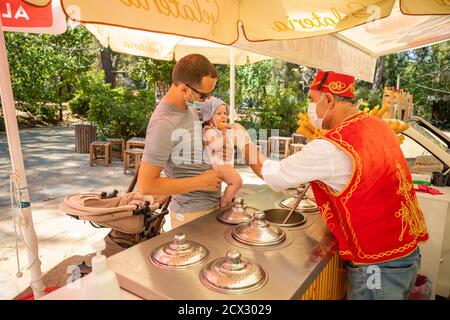 Antalya, Türkei - 4.09.2020: Verkäufer Geben Sie traditionelle türkische Eis an Mann mit Baby Mädchen an einem Sommertag in Antalya, Türkei Stockfoto