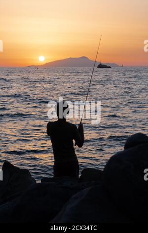 Fischer oder Angler an der Sorrentine Coast oder Peninsula in Der Sonnenuntergang gegenüber von Ischia bei Dämmerung Stockfoto