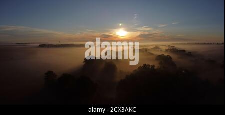 Sonnenaufgang über dem Nebel im Tal in der Nähe des Dorfes. Stockfoto