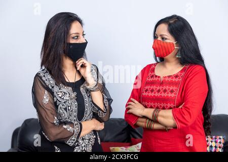 Porträt zweier indischer Frauen, die zusammen in der Covid 19 Schutzmaske stehen und die Arme gekreuzt sind. Stockfoto
