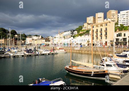 Torquay Hafen von Sonnenschein mit drohenden Wolken drohen über. Viele Fischerboote sind in der kleinen Marina vertäut Stockfoto