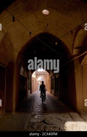 Moody späten Nachmittag Licht dringt in den Basar-Bereich, Yazd, Iran. Silhouetted Junge auf Fahrrad. Stockfoto