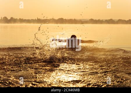 Sportlich junger Mann aktiv am See schwimmen Stockfoto