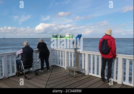 Menschen auf der berühmten Aussichtsplattform Alte Liebe und vorbeifahrenden Schiff in Cuxhaven, Norddeutschland. Hier mündet die Elbe in die Nordsee. Europa. Stockfoto