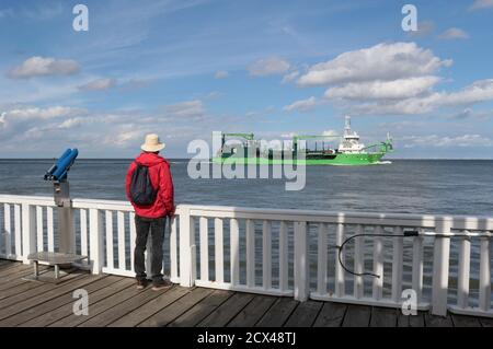 Ein Mann auf der berühmten Aussichtsplattform Alte Liebe und vorbeifahrenden Schiff in Cuxhaven, Norddeutschland. Hier mündet die Elbe in die Nordsee. Europa. Stockfoto