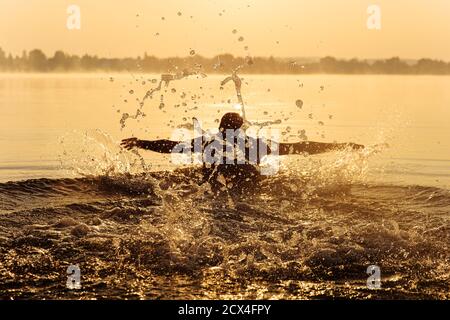 Junger Mann, der beim Schwimmen Schmetterling tief atmet Stockfoto