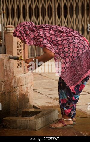 Indische Frau, die Wasser aus einem Wasserhahn nimmt. Bikaner, Rajasthan, Indien Stockfoto