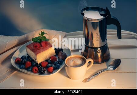 Frühstück Stillleben - Kaffeekanne, Kaffee und Dessert mit Beeren in Gelee auf der Oberseite. Klassische New Yorker Käsescheibe mit Erdbeeren, Himbeeren Stockfoto