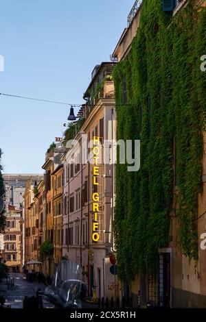 Blick auf eine typische römische Gasse im Monti-Viertel. Ivy verdeckte Gebäudefassade. Neonschild des Hotels. Rom, Italien, Europa. Stockfoto