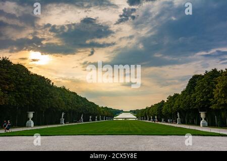 Versailles, Frankreich - 27. August 2019 : schönes Panorama der Gärten von Versailles vom Parterre d'Eau. Besucher genießen den Blick auf die Landschaft bei Sonnenuntergang. Stockfoto