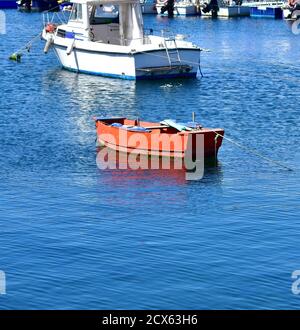 Rotes Ruderboot aus Holz, das auf dem Meer schwimmt und in einem Hafen festgemacht ist. Rias Baixas, Galicien, Spanien. Stockfoto