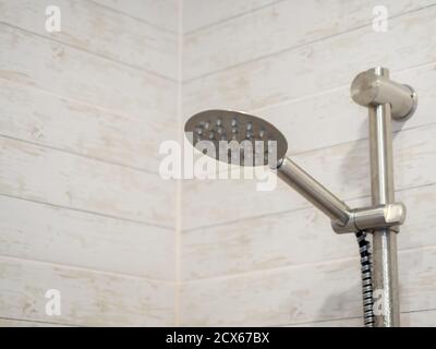 An einer Wand hängt eine silbergeflieste Dusche Fliesen imitieren ein Holz Stockfoto