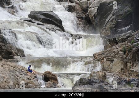 Tourist sitzt auf den Felsen am Ba Ho Wasserfall, Nha Trang, Vietnam Stockfoto