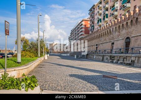 Civitavecchia, Italien - 30. Oktober 2019: Blick auf die Straße Calata della Rocca mit seinem gepflasterten Gehweg und Meer vor Steinmauer Stockfoto