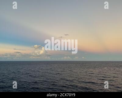 Ein wunderschöner rosa, blau und orange Sonnenuntergang über dem karibischen Meer an einem verschwommenen Abend. Stockfoto