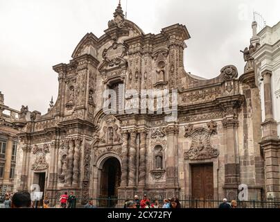 Quito, Ecuador - 2. Dezember 2008: Historische Innenstadt. Braune Steineingangsfassade zur La Compania Kirche der Jesuiten unter brauner Wolkenlandschaft wtih ped Stockfoto