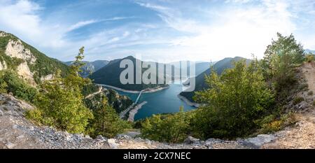 Schönes Panorama auf den Piva-See oder den Pivsko jezero in Montenegro. Blick auf die Brücke von Durmitor nach Pluzine Stadt und Berge unter dem blauen Himmel mit Wolken. Stockfoto