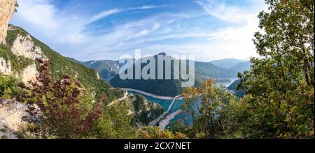 Massives Panorama auf den Piva-See oder den Pivsko jezero in Montenegro. Blick auf die Brücke von Durmitor nach Pluzine. Unglaubliche Serpentinenstraße mit Tunneln. Schöner blauer Himmel mit Wolken. Stockfoto