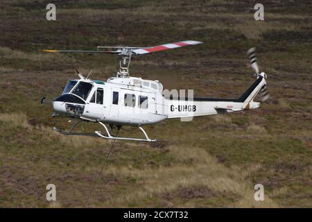 G-UHGB, eine Bell 205A-1, die von Heli-Lift Services betrieben wird, führt Pylonen-Abbauarbeiten in den Hügeln von Renfrewshire/Inverclyde in Schottland durch. Stockfoto