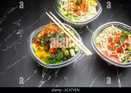 Japanische Gerichte zum Mitnehmen auf schwarzem Marmorboden, Poke, japanische Gewürze, Wakame, Edamame. Stockfoto
