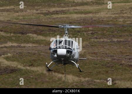 G-UHGB, eine Bell 205A-1, die von Heli-Lift Services betrieben wird, führt Pylonen-Abbauarbeiten in den Hügeln von Renfrewshire/Inverclyde in Schottland durch. Stockfoto