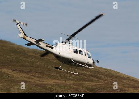 G-UHGB, eine Bell 205A-1, die von Heli-Lift Services betrieben wird, führt Pylonen-Abbauarbeiten in den Hügeln von Renfrewshire/Inverclyde in Schottland durch. Stockfoto