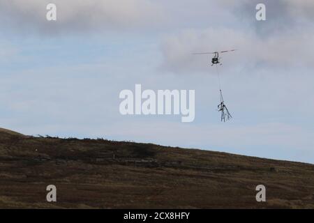 G-UHGB, eine Bell 205A-1, die von Heli-Lift Services betrieben wird, führt Pylonen-Abbauarbeiten in den Hügeln von Renfrewshire/Inverclyde in Schottland durch. Stockfoto