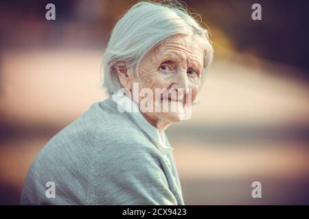 Porträt einer älteren Frau im Park, die die Kamera anschaut Stockfoto