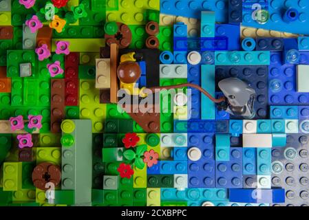 Florianopolis, Brasilien. 20. September 2020: Draufsicht auf den Mann Minifigur sitzt auf einer Holzbank am Ufer des Meeres Fischerei auf einen Hai. Moment der Entspannung Stockfoto