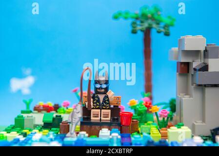 Florianopolis, Brasilien. 20. September 2020: Batman Minifigur sitzt auf einer Holzbank und genießt seinen Urlaub und Angeln am Fluss neben einem Hügel Stockfoto