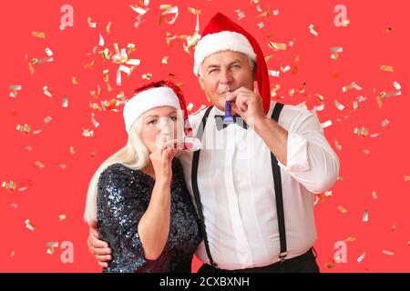 Älteres Paar feiert Neujahr auf farbigem Hintergrund Stockfoto