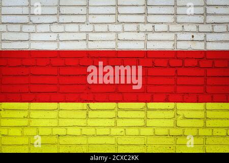 Nationalflagge von Ossetien, die in Farbfarben auf einer alten Ziegelmauer dargestellt ist. Flagge Banner auf Backstein Wand Hintergrund. Stockfoto