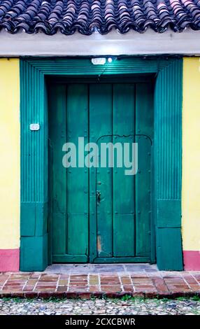Trinidaad, Kuba 26.November 2017 - Geschlossene grüne Holztür auf Gelbe und Rote Wand Stockfoto