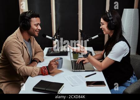 Portait von zwei Radio-Hosts, junge Mann und Frau im Gespräch miteinander während der Moderation einer Live-Show im Studio Stockfoto