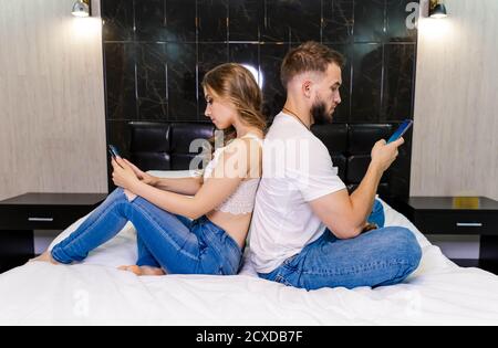 Mann und Frau, die sich auf dem Bett zurücklehnen Schlafzimmer zusammen Stockfoto