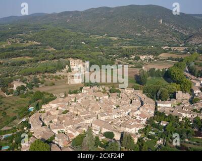 LUFTAUFNAHME. Mittelalterliches Dorf mit seiner Burg abseits des Dorfes und dem Berg Lubéron in der Ferne. Lourmarin, Vaucluse, Frankreich. Stockfoto