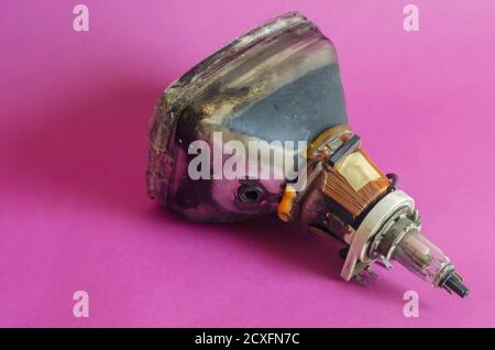 Alte Bildröhre auf einem rosa Hintergrund. Ein veralteter Teil der Nahaufnahme des Fernsehers. Technologieentwicklung. Selektiver Fokus. Stockfoto