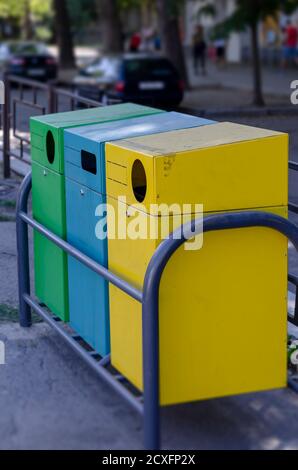 Drei mehrfarbige Müllcontainer auf einer Stadtstraße. Gelbe, blaue und grüne rechteckige Behälter zur Abfalltrennung. Ökologisches Konzept. Auswahl Stockfoto