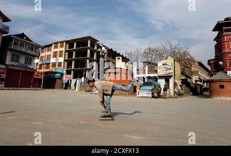 Ein Kashmiri junge Rollschuhe vorbei indische Polizisten Wachposten während eine Ausgangssperre in Srinagar 12. Februar 2013. Indien gehängt Mohammad Afzal Guru, ein Kashmiri Mann am Samstag für einen Angriff auf Parlament des Landes im Jahr 2001, Funkenbildung Auseinandersetzungen in Kaschmir zwischen Demonstranten und Polizei. Sicherheitskräfte hatten verhängte eine Ausgangssperre in Teile von Kaschmir und Menschen von der Straße bestellt. REUTERS/Dänisch Ismail (indisch verwalteten Kaschmir - Tags: Politik)