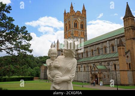 Eine Statue, die Maria und das Jesuskind vor dem Hintergrund der Buckfast Abbey in Dartmoor, South Devon, England, Juli 2017 darstellt Stockfoto