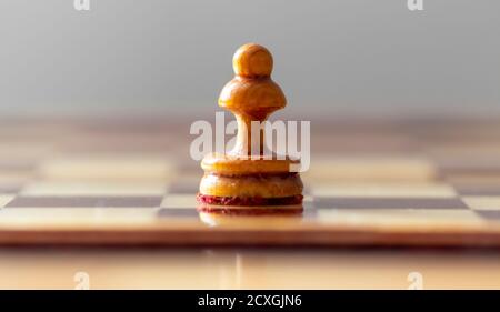 Ein Bauer steht auf einem leeren Schachbrett. Stockfoto