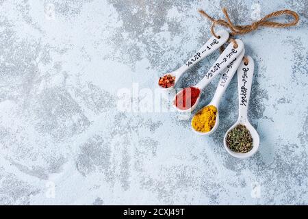 Sortiment von gemahlenen bunten Gewürzen in weiß verschiedene Keramik Messlöffel auf weißem strukturiertem Hintergrund. Mit Kopierbereich. Draufsicht Stockfoto