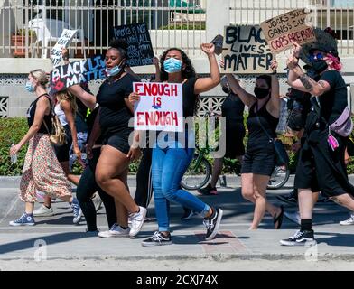 San Diego, CA / USA - 4. Juli 2020: Gruppe von Black Lives Matter weibliche Demonstranten, die auf dem Bürgersteig gehen, mit handgefertigten Protestschildern protestieren Stockfoto