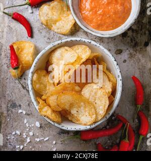 Schüsseln mit würzigen Kartoffelchips und Tomatensauce mit Meersalz und roten Chili-Paprika frisch und Pulver über alten texturellen Metall-Hintergrund. Draufsicht. Stockfoto