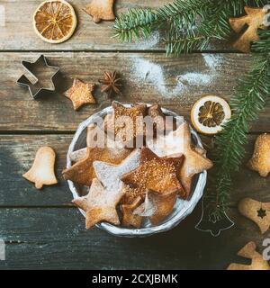 Hausgemachte Weihnachten Shortbread Stern Form Zucker Cookies in verschiedenen Größen mit Zuckerpulver, Zimt, grünen Tannenbaum und Ausstechformen auf alten Holz sur Stockfoto