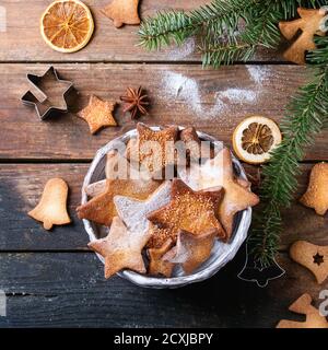 Hausgemachte Weihnachten Shortbread Stern Form Zucker Cookies in verschiedenen Größen mit Zuckerpulver, Zimt, grünen Tannenbaum und Ausstechformen auf alten Holz sur Stockfoto